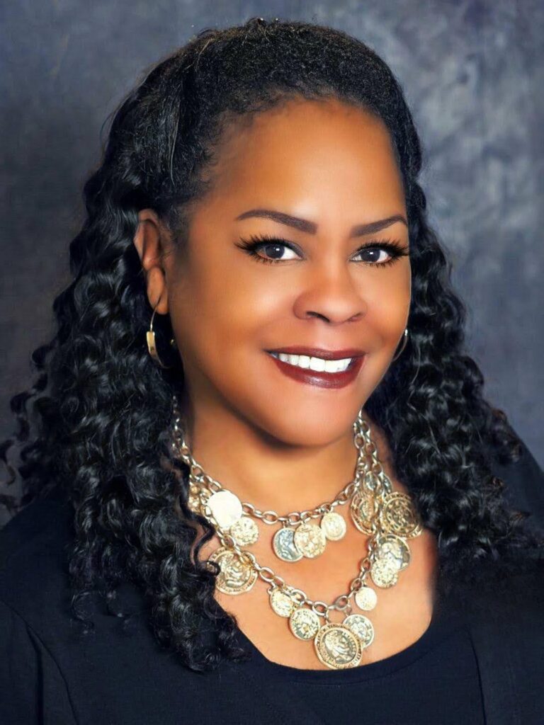 Portrait of Schéllee Y. Rocher, Village Leader at the Black Child Development Institute – Greater Los Angeles, smiling in a black top and statement necklace.