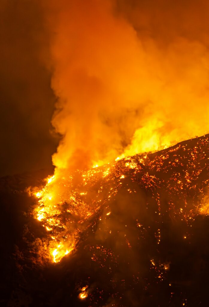 Wildfire burning through hills at night symbolizing loss and renewal.